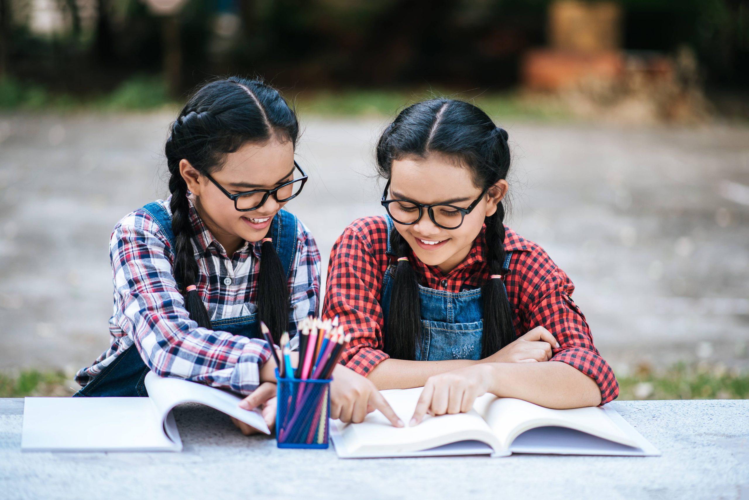 "Two girls studying together in a natural outdoor environment."