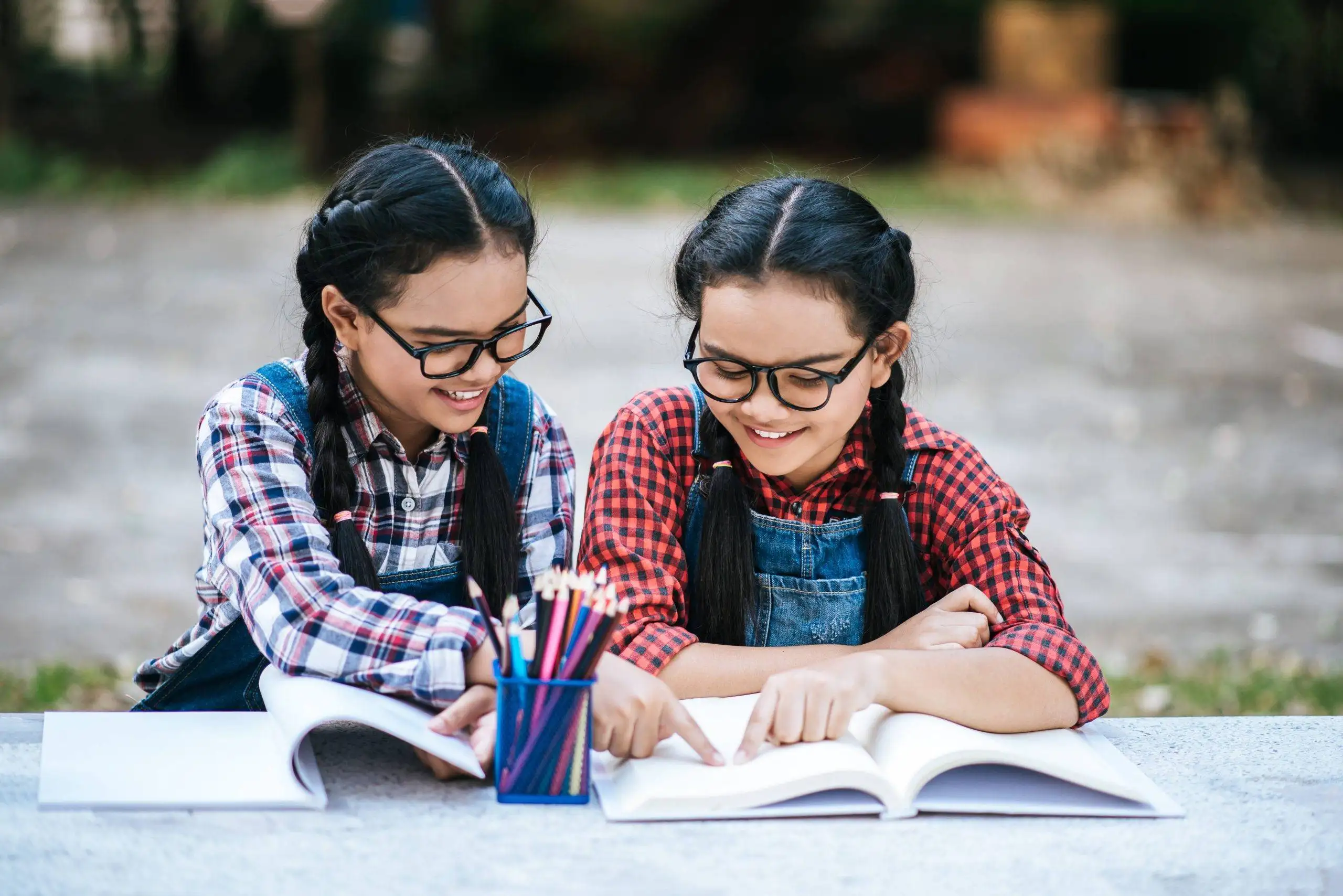 "Two girls studying together in a natural outdoor environment."