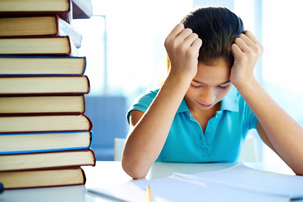 Stressed student overwhelmed with studies, holding head in frustration.